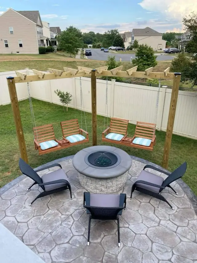 Backyard pergola with swings around a stone fire pit