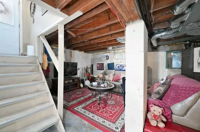 Basement before renovation with an exposed ceiling and stairs