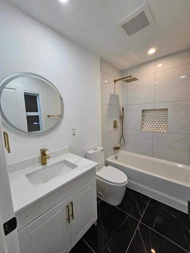 Bathroom renovation with large-format tile, recessed shower niche and gold fixtures