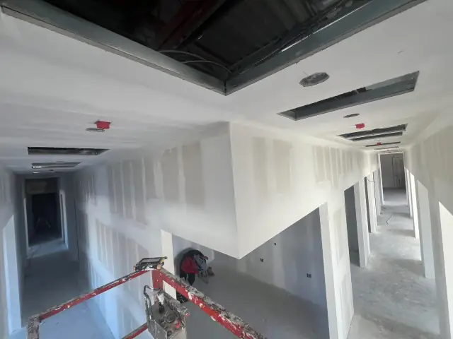 Commercial corridor with new drywall and ceiling work in progress