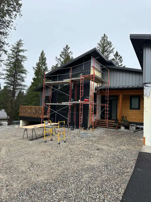 Home exterior renovation with scaffolding and dark siding