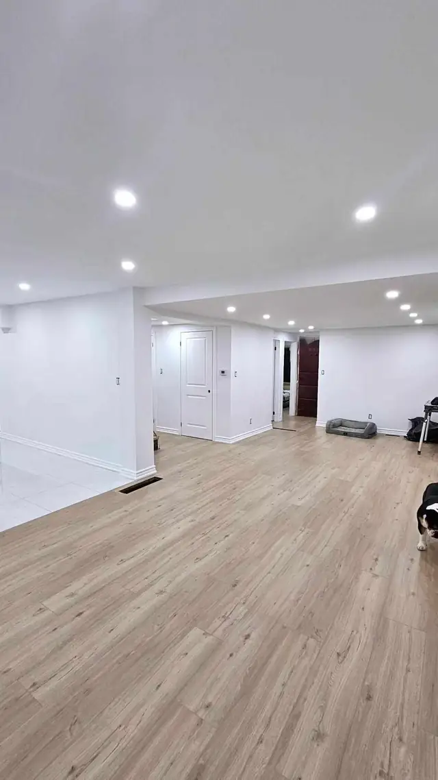Freshly painted finished basement with light flooring