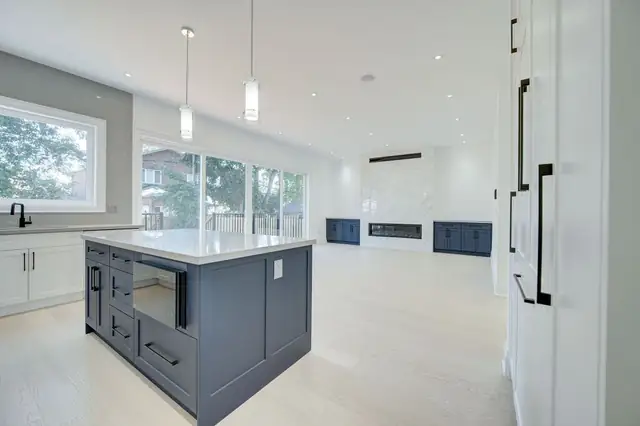Open-concept kitchen with a grey island and white wall cabinets