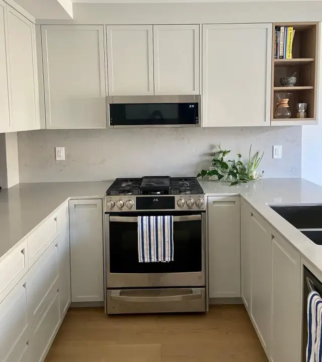 Kitchen with grey quartz countertops, gas range and over-the-range microwave