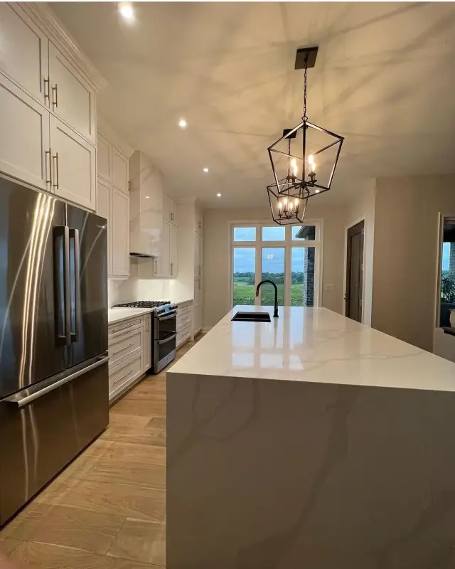 Kitchen with a marble-look waterfall island and black pendant lights