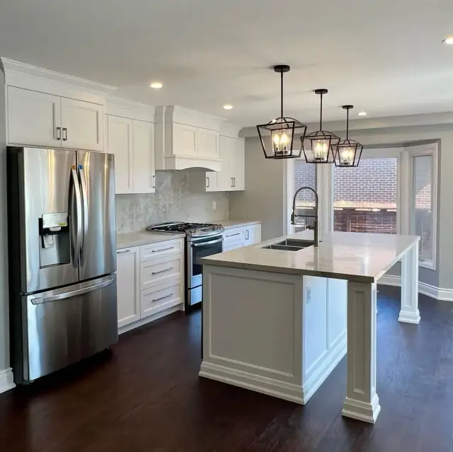 Kitchen renovation with white shaker cabinets, quartz island and lantern pendant lights