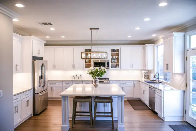 Renovated white kitchen with a large island, pendant lights and stainless appliances