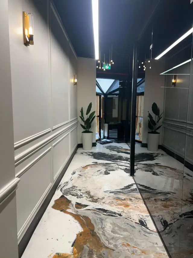 Restaurant entrance with wainscoting, wall sconces and marble-look floor